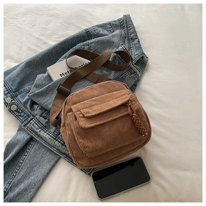 Close-up of brown corduroy crossbody bag with adjustable strap and front pocket detail
