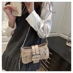 Detail of beige shoulder bag with silver studs and Y2K style metal buckle on the wide strap