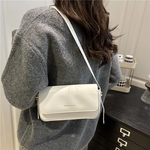 Minimalist white patent leather square crossbody bag styled with a gray knit sweater