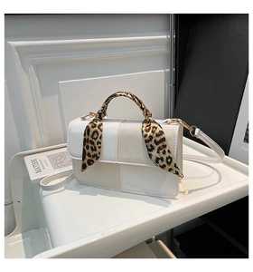 Detail of white glossy crossbody bag with leopard print scarf and gold metal hardware