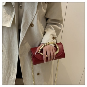 Detail of red leather handbag featuring large gold circular handle and gold chain strap