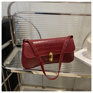 Detailed view of dark red faux leather baguette bag with crocodile texture and gold clasp