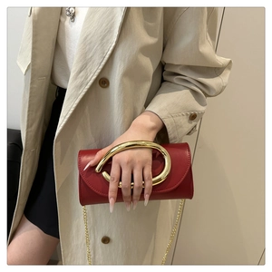 Detail of red leather evening bag with large gold ring handle and metal chain strap