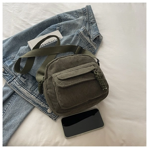 Detail of army green corduroy crossbody bag with woven zipper pull and adjustable strap