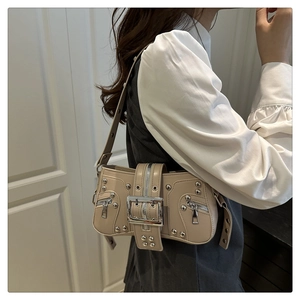Close-up of beige leather shoulder bag with silver punk rivets and Y2K metal hardware