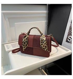Detail of color-block crossbody bag featuring contrast leather and leopard scarf handle