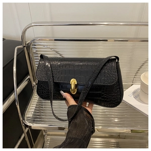 Detail of black crocodile texture baguette bag with a gold capsule twist lock closure