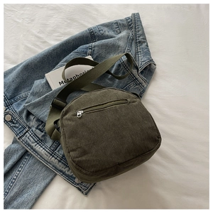 Detail of army green corduroy crossbody bag featuring a metal zipper pocket and wide strap
