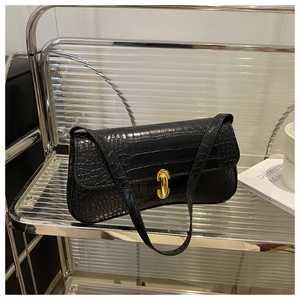Close-up of black crocodile embossed baguette bag with a shiny gold turn-lock closure