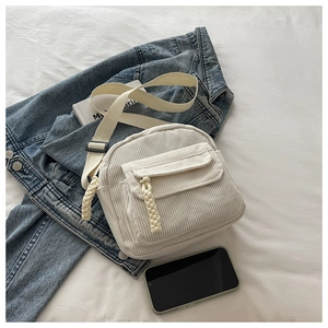Detail of off-white corduroy crossbody bag with woven rope zipper and wide strap