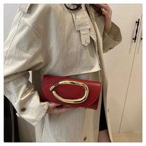 Close-up of a red leather clutch bag with a large gold metal buckle and elegant chain strap