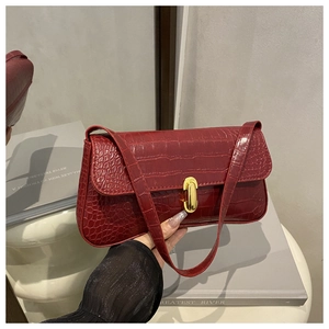 Macro detail of wine red crocodile embossed texture with golden oval swivel metal lock