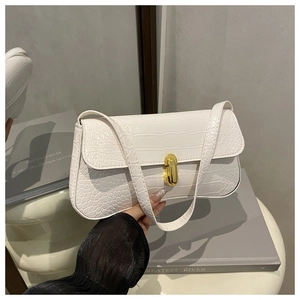 Detail of white crocodile texture baguette bag with a golden metal twist-lock clasp