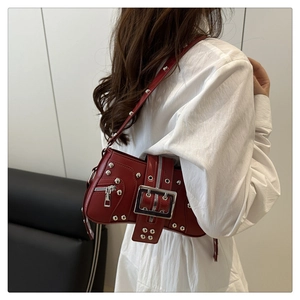 Sac bandoulière rouge foncé avec rivets argentés sur un modèle pour un style urbain