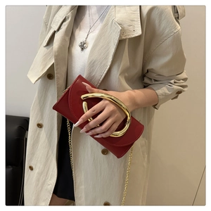 Detail of red clutch with large gold metal ring handle and fine gold chain strap