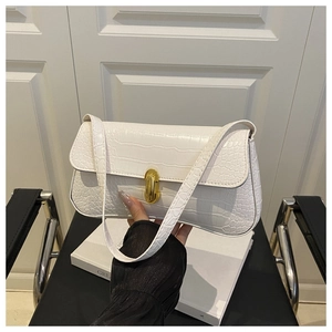 Detailed view of white crocodile pattern baguette bag with golden rotating metal buckle