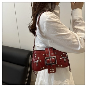 Close-up of wine red leather punk shoulder bag with silver rivets and large metal buckle