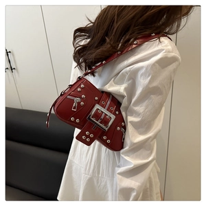Détail du sac rouge punk avec rivets argentés et boucle métallique porté par un modèle