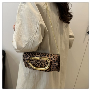 Detail of leopard print chain bag with gold oval buckle handle on beige trench coat