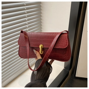 Close-up of retro burgundy baguette bag with crocodile pattern and golden metal clasp