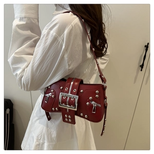 Détail d'un sac bandoulière rouge style punk avec rivets argentés et boucle métallique