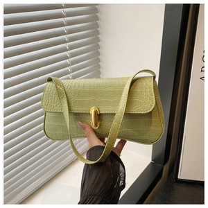Close-up of light green crocodile embossed baguette bag featuring a gold cylindrical lock
