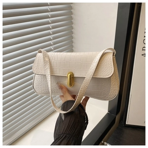 Detail of white crocodile embossed baguette bag with golden metal buckle and shoulder strap