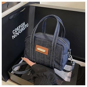 Detail of dark blue denim mini bag with contrast stitching in a gift box packaging
