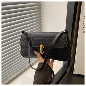 Detail of black crocodile pattern shoulder bag featuring a shiny gold metal twist lock