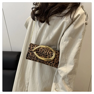 Chic leopard print box bag with gold metal buckle shown on a trench coat model