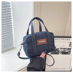 Detail of vintage blue denim mini bag with contrast stitching and brown leather patch
