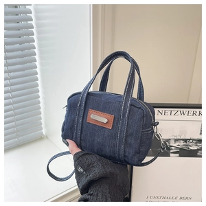 Detail of vintage navy denim mini pillow bag with white stitching and leather patch
