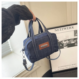Detailed view of a vintage denim handbag with brown leather logo and white contrast stitching