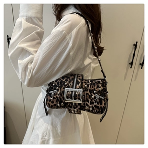 Détail du sac à main léopard avec rivets argentés et boucle métallique sur robe blanche