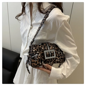 Detail of leopard print crossbody bag with silver buckles and studs on a model