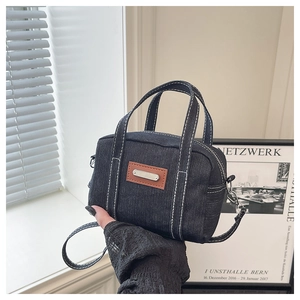 Detail of vintage navy denim handbag with contrast stitching and metal logo plaque