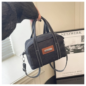 Detailed shot of retro denim boston bag featuring white contrast stitching and top handles