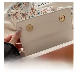 Detail view of the magnetic closure and embroidered strap on the color-block bag