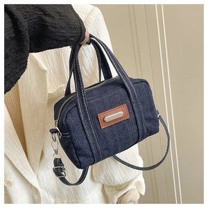 Close-up of a vintage dark blue denim mini bag with brown leather tag and silver hardware