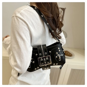 Détail d'un sac à bandoulière punk noir avec rivets et boucle sur un pull en maille blanc