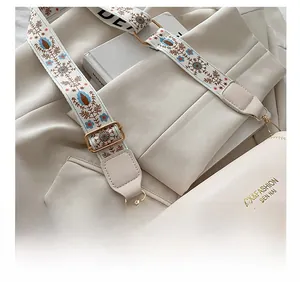 Detail of adjustable bohemian embroidered strap on a beige crossbody square bag