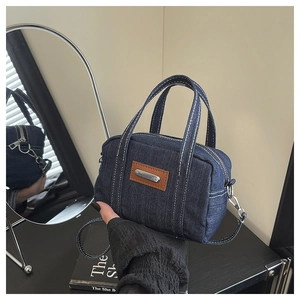 Detailed close-up of dark denim mini pillow bag with brown leather patch and dual handles