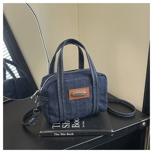Detail of vintage denim mini boston bag with contrast stitching and leather patch