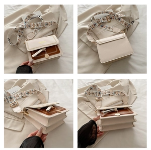 Detail view of cream and brown crossbody bag with multi-compartment design and wide strap