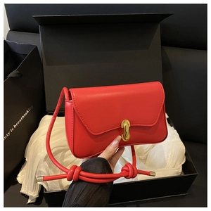 Détail du sac bandoulière en cuir rouge avec fermoir doré rotatif et coffret cadeau luxe