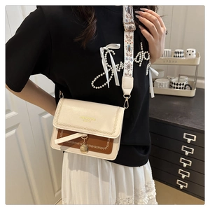 Detail view of stylish crossbody bag with colorful embroidered wide strap and flap