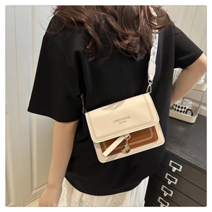Detail of crossbody square bag with wide geometric strap and metal circular charm