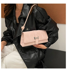 Detail showing pale pink baguette bag with glossy wrinkled texture and silver buckle