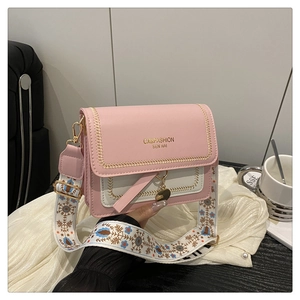 Detail of pink crossbody bag with floral embroidery strap and metal pendant charm