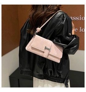 Détail du sac baguette rose clair montrant la texture craquelée et la boucle H argentée